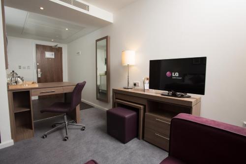 a hotel room with a desk with a tv and a desk at Staybridge Suites Birmingham, an IHG Hotel in Birmingham
