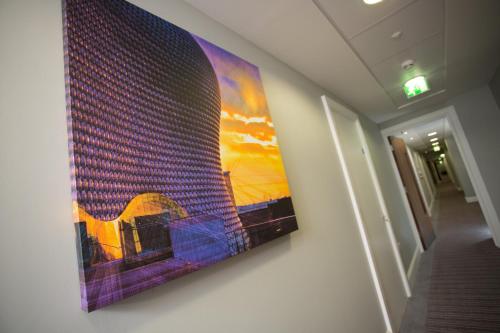 a painting hanging on a wall in a hallway at Staybridge Suites Birmingham by IHG in Birmingham