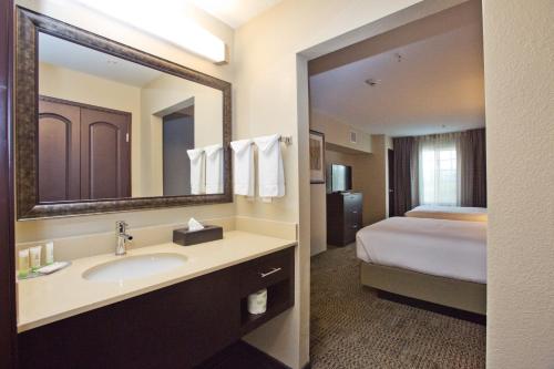 a bathroom with a sink and a bed and a mirror at Staybridge Suites Austin South Interstate Hwy 35 by IHG in Austin