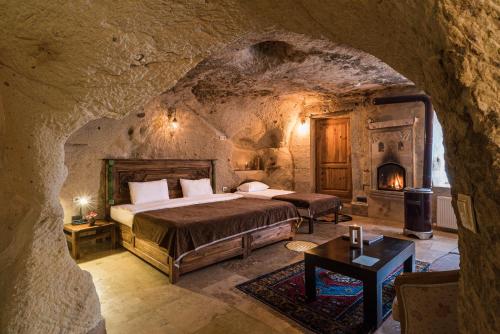 a bedroom with a bed and a fireplace in a cave at Atilla's Cave Hotel in Nevşehir