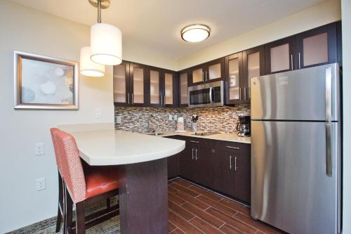 a kitchen with a table and a refrigerator at Staybridge Suites Austin South Interstate Hwy 35 by IHG in Austin