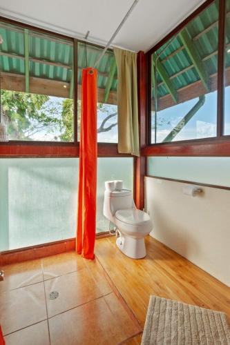 a bathroom with a toilet in a room with windows at Anamaya Resort in Montezuma