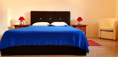 a bedroom with a blue bed with two tables and a chair at Charme de Monsaraz II in Monsaraz