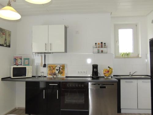 Una cocina con gabinetes blancos y una encimera negra. en Gästehaus Holiday, en Witten