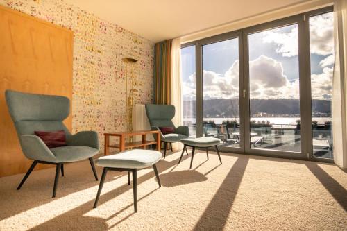a living room with two chairs and a large window at Seehotel Adler in Bodman-Ludwigshafen