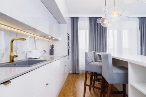 uma cozinha com balcões brancos e um lavatório e cadeiras em NY Residence Apartments Wrocławska Cracow by Renters Prestige em Cracóvia