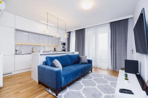 uma sala de estar com um sofá azul e uma cozinha em NY Residence Apartments Wrocławska Cracow by Renters Prestige em Cracóvia