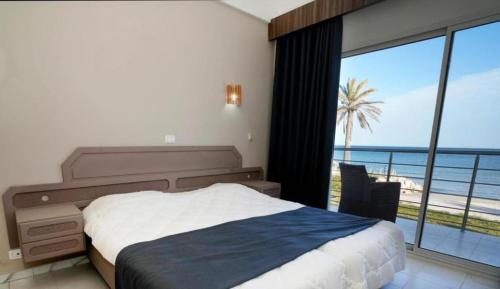 a bedroom with a bed and a view of the ocean at Palmyra Club Nabeul in Nabeul