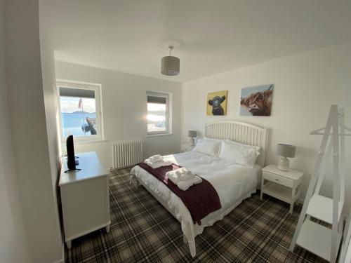 a bedroom with a white bed and a desk and windows at 4 South Beach Stornoway in Stornoway