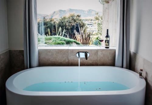 a bath tub in front of a window with a bottle of wine at The Hidden Spring in Wanaka