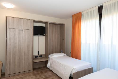 a bedroom with two beds and a cabinet with a television at Hotel Donatello Imola in Imola