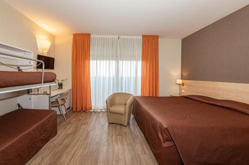 a hotel room with two beds and a desk at Hotel Donatello Imola in Imola