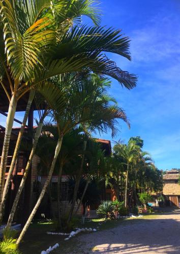 a group of palm trees in front of a building at Pousada Halliny do Rosa in Praia do Rosa