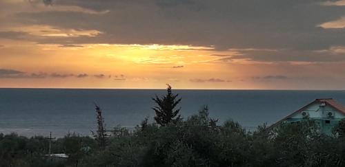 a sunset over the ocean with a house in the foreground at Agrotourism Himara in Himare