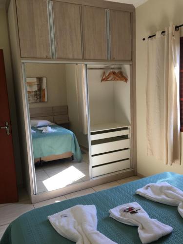 a bedroom with a mirror and a bed with towels at recanto palmeira imperial Holambra SP in Holambra