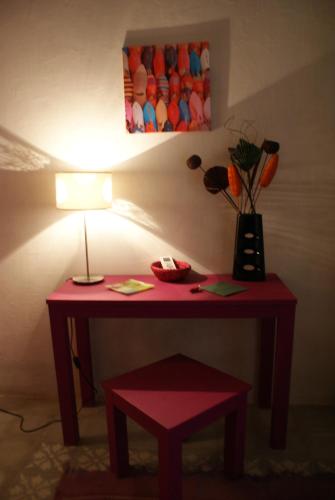 a red table with a lamp and a vase of flowers at Riad Safir in Meknès