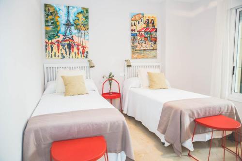 2 Betten in einem Zimmer mit roten Stühlen in der Unterkunft Luxury Apartment Guadalmina Golf - Marbella in Marbella