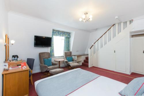 a bedroom with a bed and a living room at OYO Stade Court Hotel in Hythe