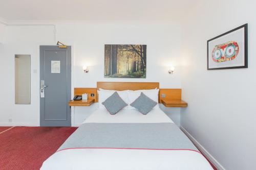 ein Schlafzimmer mit einem großen weißen Bett mit zwei Kissen in der Unterkunft OYO Stade Court Hotel in Hythe