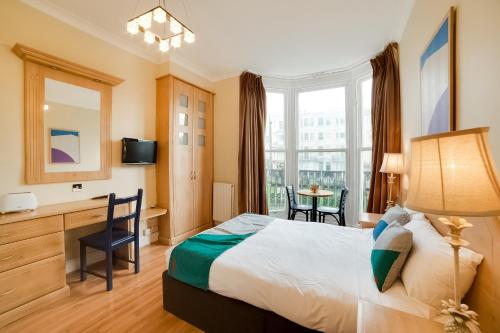 Habitación de hotel con cama, escritorio y ventana en The Gullivers Hotel en Brighton & Hove