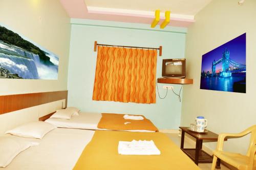 Habitación con 2 camas, mesa y TV. en Hotel Sai Darshan, en Shirdi
