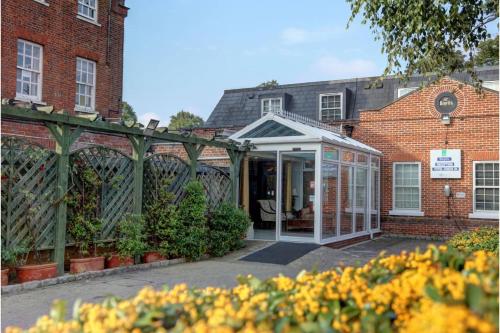 a greenhouse in front of a brick building with flowers at SK Baylis House Hotel in Slough