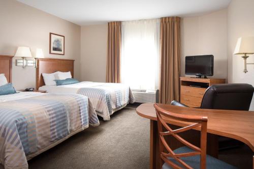 Habitación de hotel con 2 camas, escritorio y TV. en Candlewood Suites La Crosse, an IHG Hotel, en La Crosse