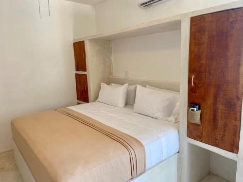 a small bedroom with a bed with a wooden door at MIO Cancún Hotel Boutique in Cancún