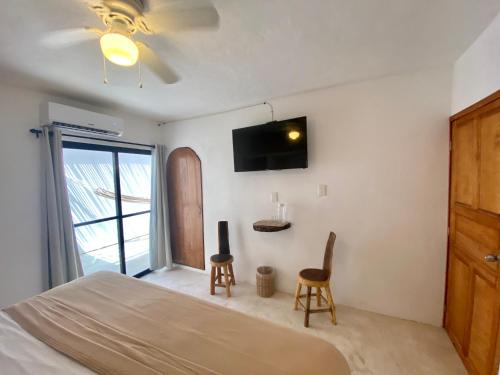 a bedroom with a bed and two chairs and a tv at MIO Cancún Hotel Boutique in Cancún