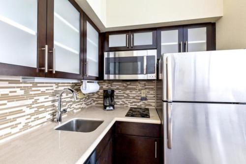 a kitchen with a refrigerator and a sink at Staybridge Suites College Station by IHG in College Station