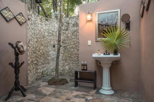 a bathroom with a sink next to a stone wall at Playa Esperanza Tulum in Tulum