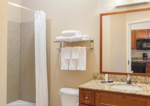 a bathroom with a toilet and a sink and a mirror at Candlewood Suites Georgetown, an IHG Hotel in Georgetown