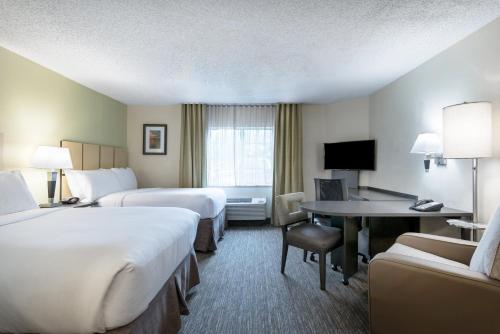 a hotel room with two beds and a desk at Candlewood Suites Lake Mary, an IHG Hotel in Lake Mary