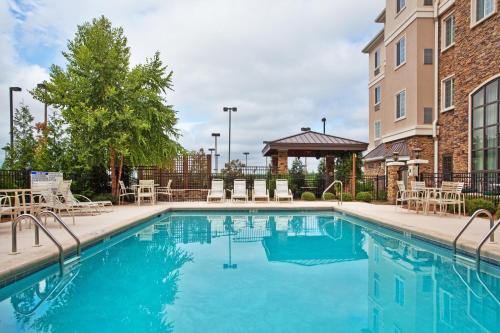 a swimming pool with chairs and a building at Staybridge Suites Columbus - Fort Benning by IHG in Columbus