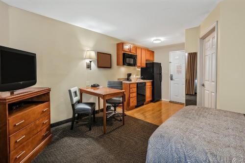 a hotel room with a bed and a desk and a kitchen at Candlewood Suites Galveston by IHG in Galveston