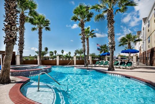 a swimming pool with palm trees in a resort at Candlewood Suites Galveston by IHG in Galveston