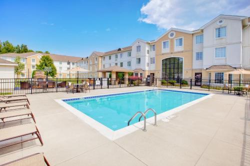 a swimming pool with chairs and a building at Staybridge Suites Cleveland Mayfield Heights Beachwood, an IHG Hotel in Mayfield Heights