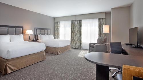 a hotel room with two beds and a desk at Candlewood Suites Grand Island by IHG in Grand Island