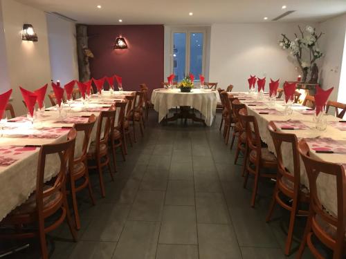 a row of tables in a room with red napkins at Hôtel de Ville in Les Verrières