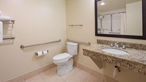 a bathroom with a toilet, sink, and mirror at Best Western Plus Bayside Inn in San Diego