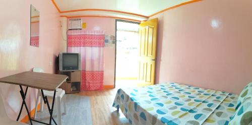 1 dormitorio con cama, mesa y TV en J&J Tourist Inn en Panglao