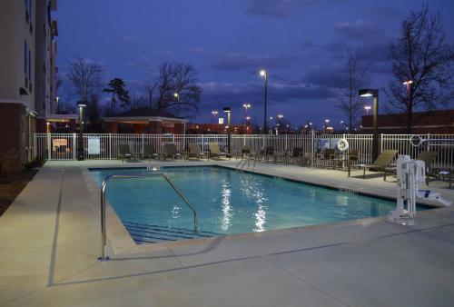 a swimming pool at night with chairs and lights at Candlewood Suites Greenville by IHG in Greenville