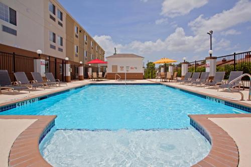 een zwembad in een hotel met stoelen en een gebouw bij Candlewood Suites Houston Westchase - Westheimer, an IHG Hotel in Houston