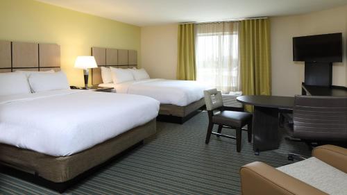 a hotel room with two beds and a desk at Candlewood Suites - Newark South - University Area by IHG in Newark