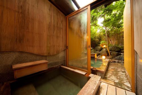 a bath tub in a room with a window at Kappo Ryokan Kannawa Bettei in Beppu