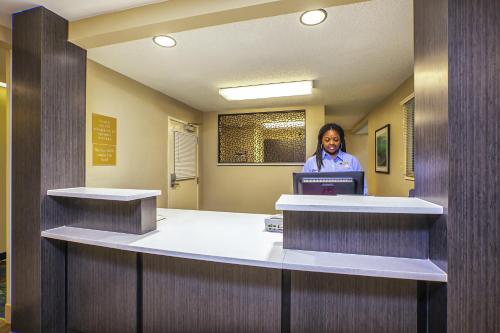 a woman standing at a desk in a waiting room at Candlewood Suites Indianapolis Northeast, an IHG Hotel in Indianapolis