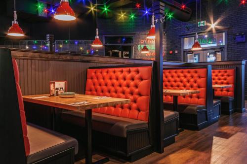 a restaurant with red booths and a wooden table at Holiday Inn St Johns by IHG in St. John's