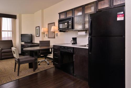 a kitchen with a black refrigerator and a desk at Candlewood Suites Terre Haute by IHG in Terre Haute