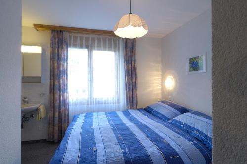 a bedroom with a bed with a blue striped blanket at Haus Alpenglück in Saas-Fee