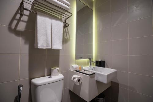 a bathroom with a white toilet and a sink at Ramada Meridin Johor Bahru in Nusajaya
